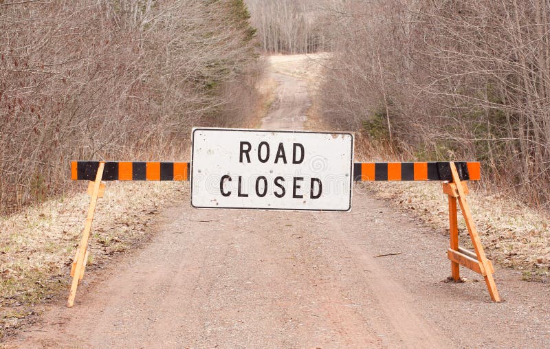 Road closed sign on rural unpaved road. Road closed sign on rural unpaved road.