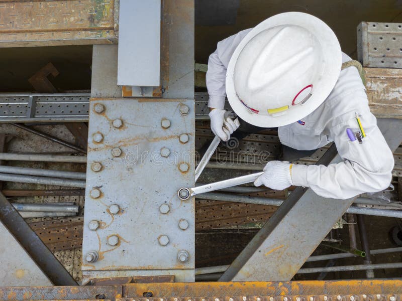 De werknemers gebruiken een moersleutel tot koppelbouten om de splikplaat vast te houden aan de staalbundel waarop de staalconstru