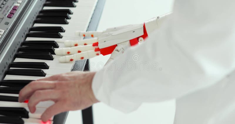 De wetenschapperingenieur speelt de piano met robotachtige prothesehand Het spelen van twee handen, een robotachtige prothetische