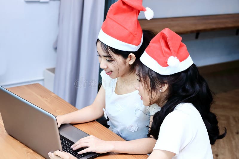 De wijnoogst stemde beeld van vrolijke jonge Aziatische vrouwen die in Kerstmanhoeden online met laptop in woonkamer thuis winkel royalty-vrije stock foto's De wijnoogst stemde beeld van vrolijke jonge Aziatische vrouwen die in Kerstmanhoeden online met laptop in woonkamer thuis winkel royalty-vrije stock foto's