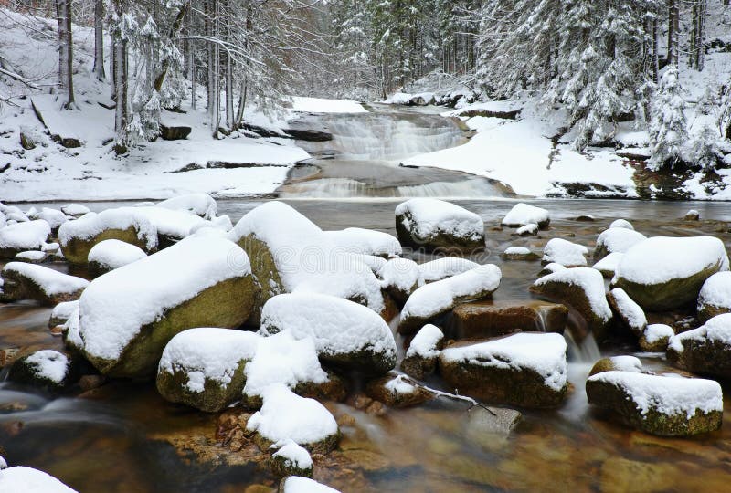 De winter bij bergrivier Grote die stenen in stroom met verse poedersneeuw en lui water met low level wordt behandeld royalty-vrije stock fotografie De winter bij bergrivier Grote die stenen in stroom met verse poedersneeuw en lui water met low level wordt behandeld royalty-vrije stock fotografie
