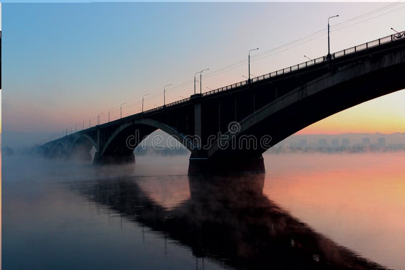 De wintercityscape met een overspannen brug bij zonsondergang stock afbeelding De wintercityscape met een overspannen brug bij zonsondergang stock afbeelding