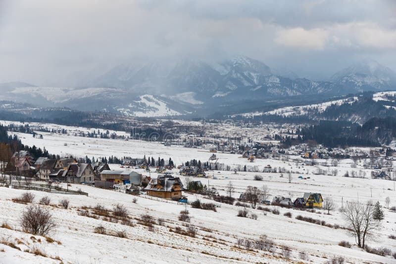 De winterlandschap van de Bergen van Polen Tatra Snow-covered Vallei met Vele Traditionele Poolse Huizen bij de Achtergrond van s stock foto's De winterlandschap van de Bergen van Polen Tatra Snow-covered Vallei met Vele Traditionele Poolse Huizen bij de Achtergrond van s stock foto's