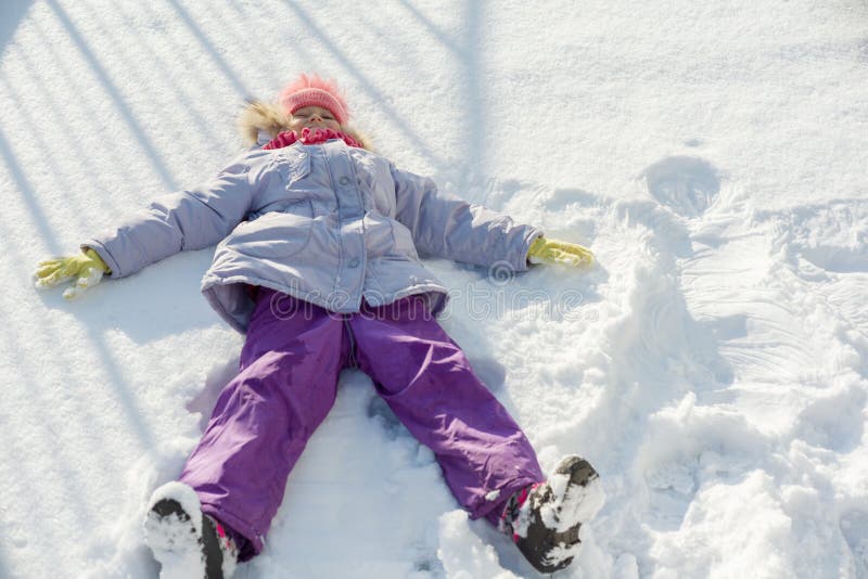 De winterportret die van vrolijk kindmeisje die pret in de sneeuw hebben, op de sneeuw in de vorm van engel, hoogste mening ligge royalty-vrije stock afbeeldingen De winterportret die van vrolijk kindmeisje die pret in de sneeuw hebben, op de sneeuw in de vorm van engel, hoogste mening ligge royalty-vrije stock afbeeldingen