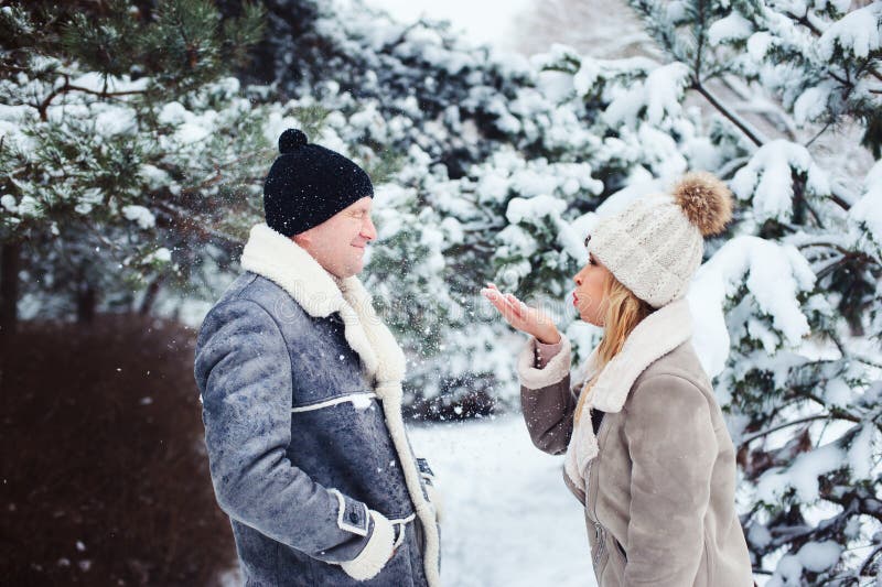 de winterportret van gelukkige paar speel, blazende sneeuw en het besteden goede dag openlucht in sneeuwbos stock fotografie de winterportret van gelukkige paar speel, blazende sneeuw en het besteden goede dag openlucht in sneeuwbos stock fotografie