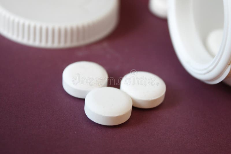 de witte capsules goten uit de container, rood, de achtergrond van Bourgondi?, close-up stock afbeeldingen de witte capsules goten uit de container, rood, de achtergrond van Bourgondi?, close-up stock afbeeldingen