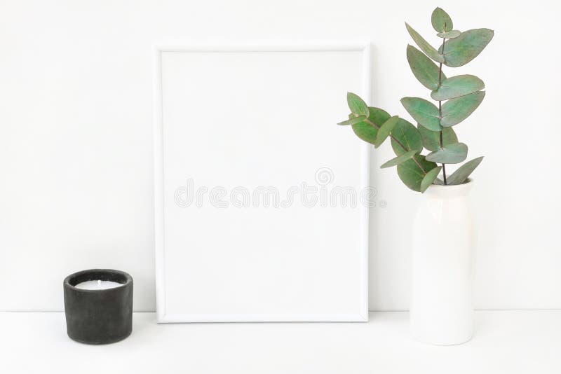 De witte samenstelling van het kadermodel met takken van groene zilveren dollareucalyptus in ceramische vaas zwarte kaars op lijs stock foto De witte samenstelling van het kadermodel met takken van groene zilveren dollareucalyptus in ceramische vaas zwarte kaars op lijs stock foto