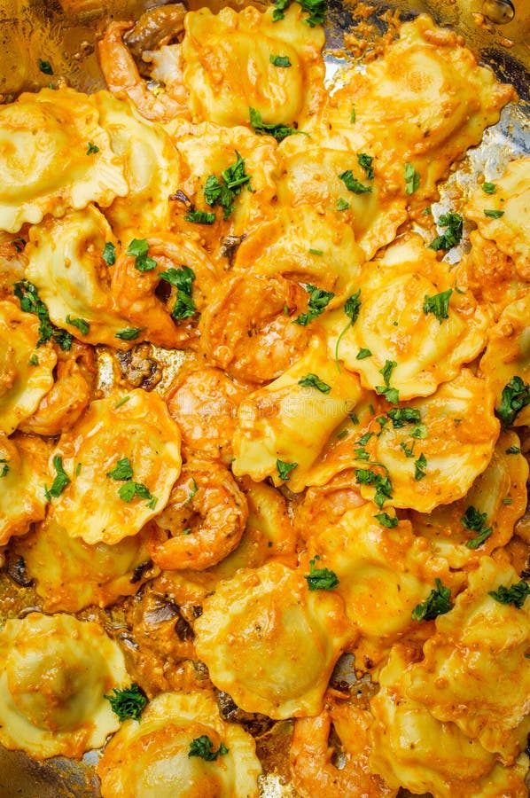 Italian shrimp and mushrooms with ravioli in pink creamy vodka sauce cooking on stovetop. Italian shrimp and mushrooms with ravioli in pink creamy vodka sauce cooking on stovetop