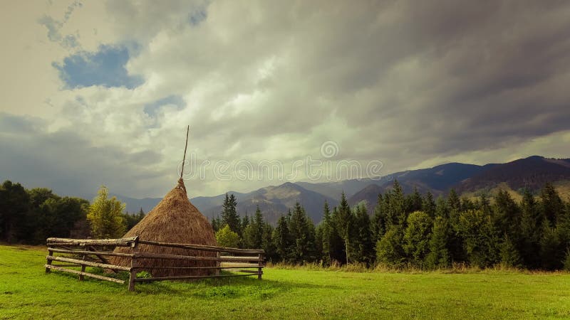 De wolken die van de tijdtijdspanne zich over mooi berglandschap bewegen met hooistapel