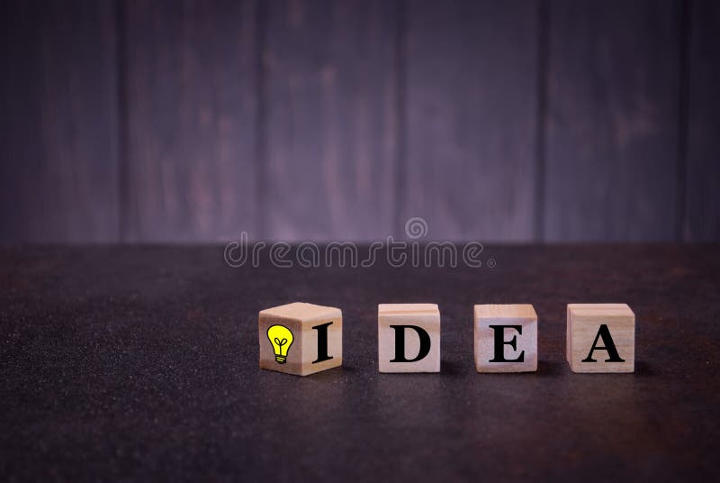 De woordidee en sigh gloeilamp op houten kubussen, op een donkere achtergrond, steekt houten kubussentekens aan stock foto De woordidee en sigh gloeilamp op houten kubussen, op een donkere achtergrond, steekt houten kubussentekens aan stock foto