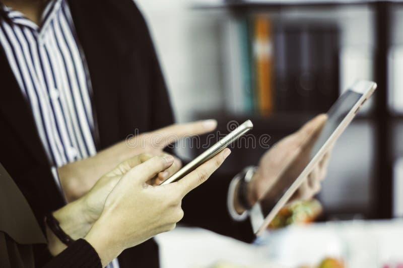 De zakenman en de bedrijfsvrouw gebruiken smartphones en tabletten die op hand met het concept gemak in online het winkelen zijn stock foto's De zakenman en de bedrijfsvrouw gebruiken smartphones en tabletten die op hand met het concept gemak in online het winkelen zijn stock foto's
