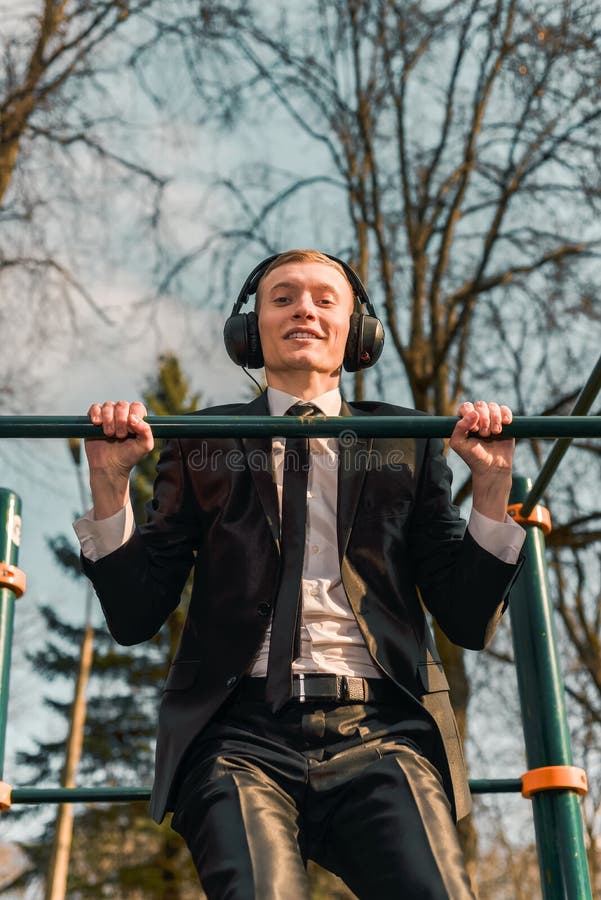 De zakenman in hoofdtelefoons heft zich op een sportenrekstok op Moderne Jonge Mens Start bedrijfsconcept royalty-vrije stock afbeeldingen De zakenman in hoofdtelefoons heft zich op een sportenrekstok op Moderne Jonge Mens Start bedrijfsconcept royalty-vrije stock afbeeldingen
