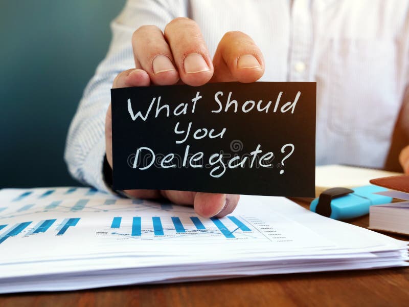 De zakenman houdt teken wat u zou moeten delegeren Delegatieconcept