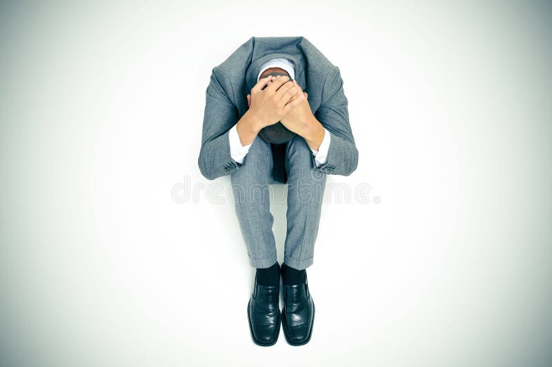 De zakenman krulde omhoog in de vloer met zijn hoofd tussen zijn kne stock afbeeldingen De zakenman krulde omhoog in de vloer met zijn hoofd tussen zijn kne stock afbeeldingen