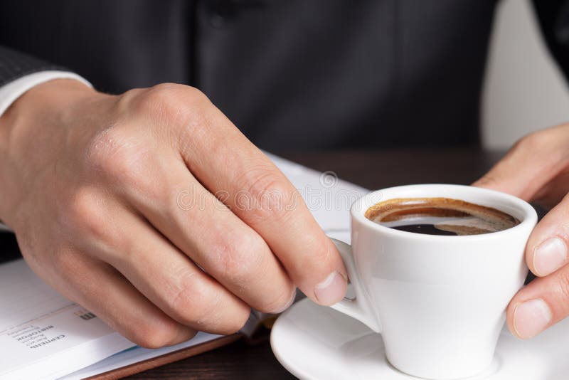 Businessman makes coffee break after work with diary. Businessman makes coffee break after work with diary