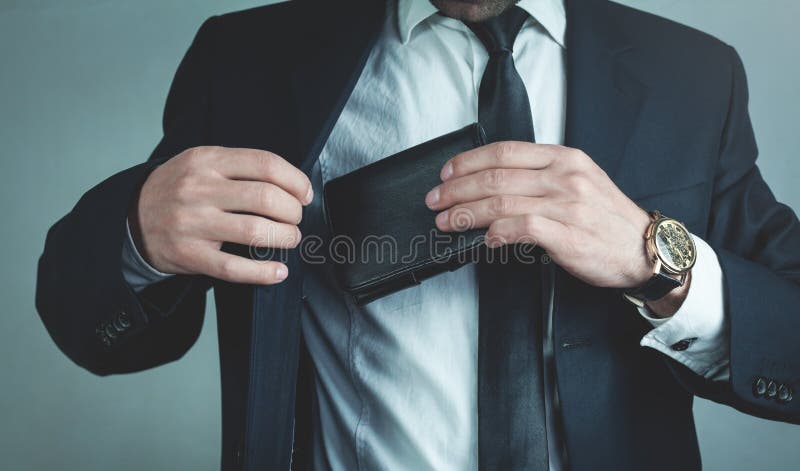 De zakenman trekt zijn leerportefeuille in kostuumzak stock foto De zakenman trekt zijn leerportefeuille in kostuumzak stock foto