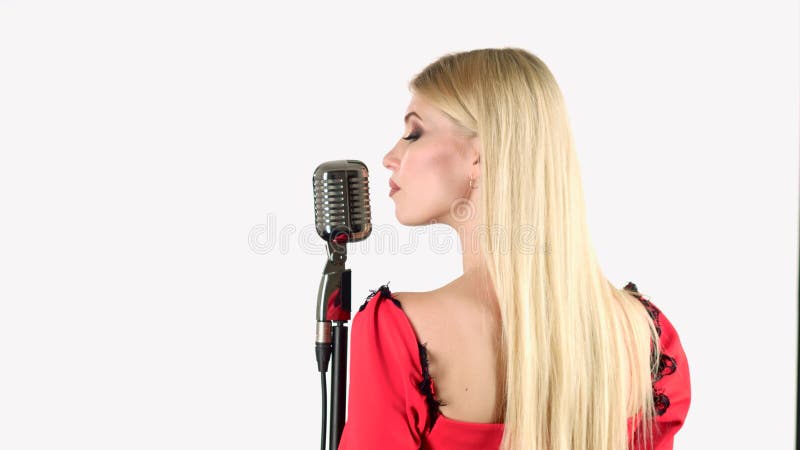 De zanger in een rode kleding zingt in een retro microfoon Witte achtergrond Achter mening
