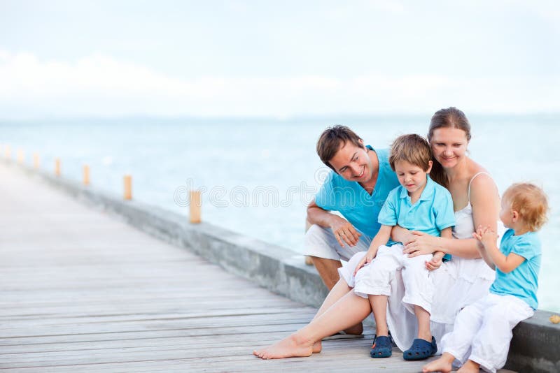 De zitting van de familie in openlucht bij kust stock afbeeldingen De zitting van de familie in openlucht bij kust stock afbeeldingen