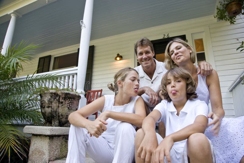De zitting van de familie samen op voorportiekstappen stock foto De zitting van de familie samen op voorportiekstappen stock foto