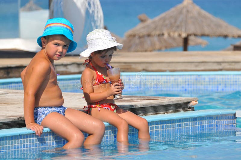 Een meisje en een jongen zitten in het zwembad en drinken royalty-vrije stock afbeeldingen