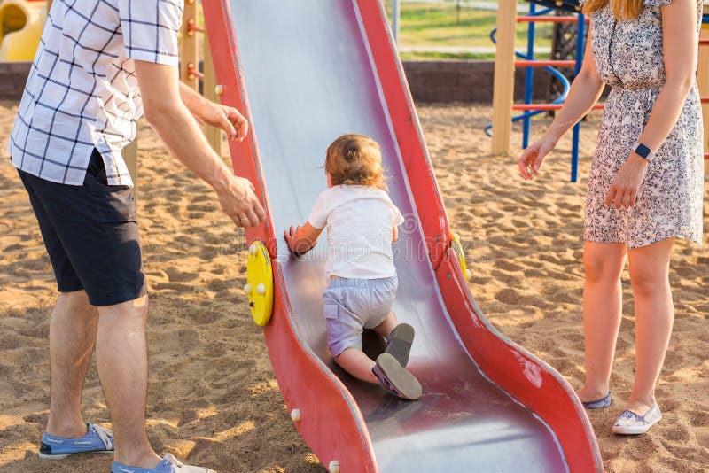 De zomer, kinderjaren, vrije tijd en familieconcept - gelukkig kind en zijn ouders op het klimrek van de kinderenspeelplaats stock foto De zomer, kinderjaren, vrije tijd en familieconcept - gelukkig kind en zijn ouders op het klimrek van de kinderenspeelplaats stock foto