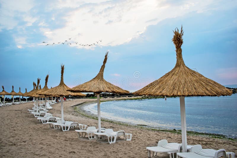 De zomer, op het strand, sunbeds en de paraplu's, vóór een onweer begint stock afbeelding De zomer, op het strand, sunbeds en de paraplu's, vóór een onweer begint stock afbeelding