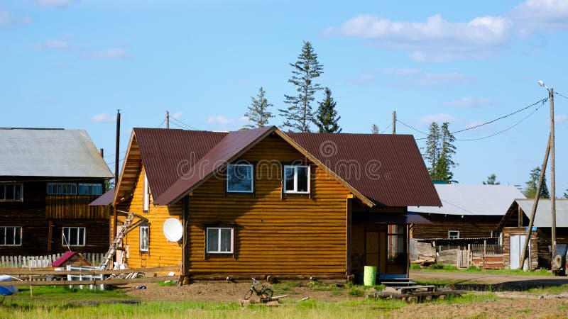 In de zomer wordt in Yakutia in het dorp een nieuw particulier huisje van gele stammen, onder de oude dorpshuizen, afgesloten royalty-vrije stock foto In de zomer wordt in Yakutia in het dorp een nieuw particulier huisje van gele stammen, onder de oude dorpshuizen, afgesloten royalty-vrije stock foto