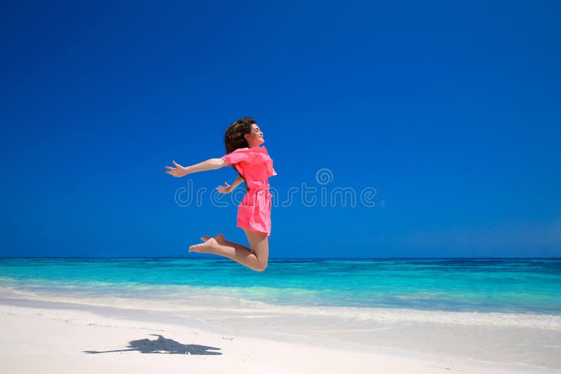 De zomerplezier Gelukkige jonge vrouw die op het overzees, brunette springen