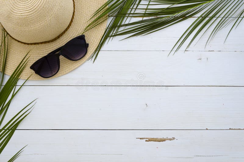 De zomervakantie, reis, vakantie, strandconcept Zonhoed, zonnebril en tropische palmbladen op witte houten raad bovenkant stock foto De zomervakantie, reis, vakantie, strandconcept Zonhoed, zonnebril en tropische palmbladen op witte houten raad bovenkant stock foto