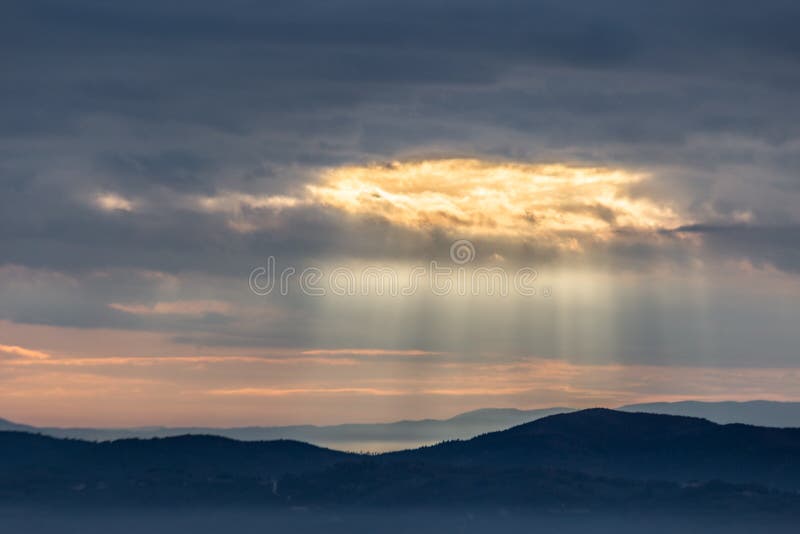 De zonnestraal glanst door wolken over de bergen en een overzees van mist stock foto De zonnestraal glanst door wolken over de bergen en een overzees van mist stock foto