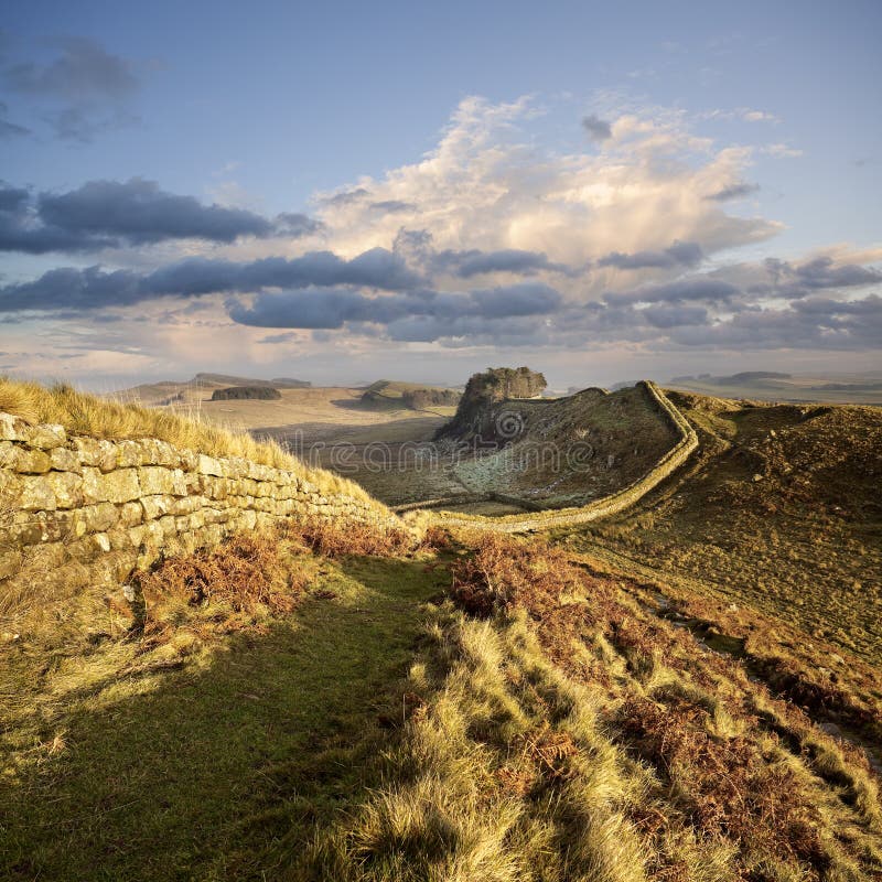 Hadrian`s Wall snakes its way across the landscape in Northumberland, England, illuminated by a pastel winter sunset. Hadrian`s Wall snakes its way across the landscape in Northumberland, England, illuminated by a pastel winter sunset