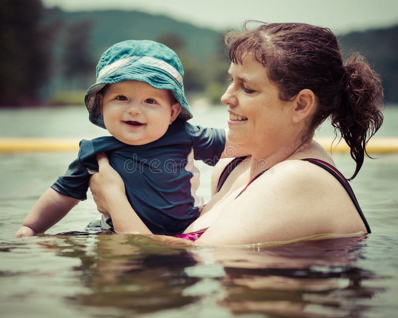 De zoon van de de zuigelingsbaby van het moederonderwijs om in meer te zwemmen stock foto's De zoon van de de zuigelingsbaby van het moederonderwijs om in meer te zwemmen stock foto's