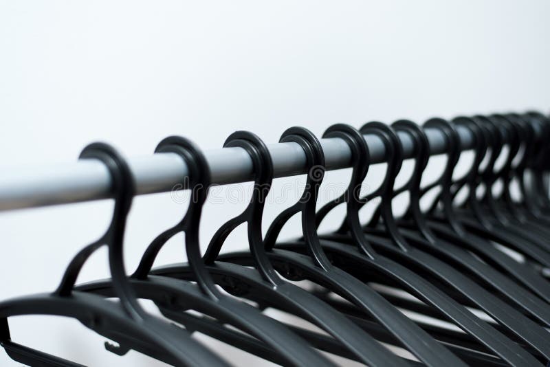 de zwarte plastic hangers hangen op een lichte achtergrond vele verschillende hangers stock fotografie de zwarte plastic hangers hangen op een lichte achtergrond vele verschillende hangers stock fotografie