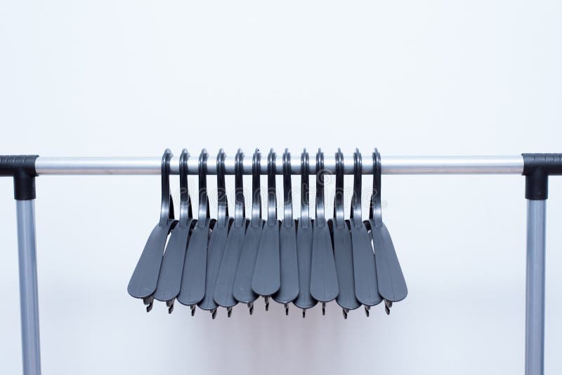 De zwarte plastic hangers hangen op een lichte achtergrond vele verschillende hangers Het rek van de vloerlaag stock fotografie De zwarte plastic hangers hangen op een lichte achtergrond vele verschillende hangers Het rek van de vloerlaag stock fotografie