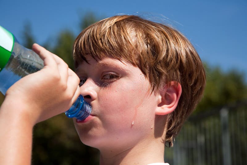De zwetende Jongen is drinkwater uit een fles stock foto's De zwetende Jongen is drinkwater uit een fles stock foto's
