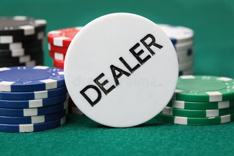 Dealer button and poker chips on a green surface.