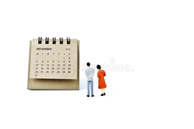 December. Calendar sheet and miniature plastic man and woman on