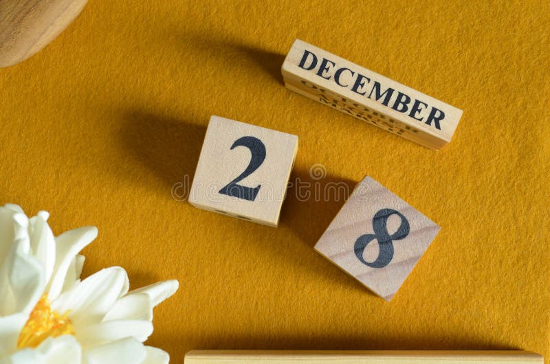 December 28, Wooden Calendar cube with yellow felt fabric with peony flower for date icon background. royalty free stock photos