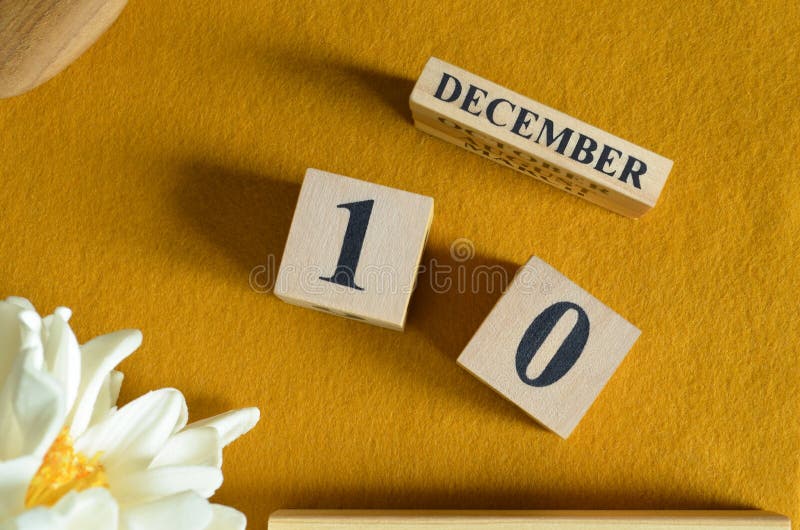December 10, Wooden Calendar cube with yellow felt fabric with peony flower for date icon background. royalty free stock photos