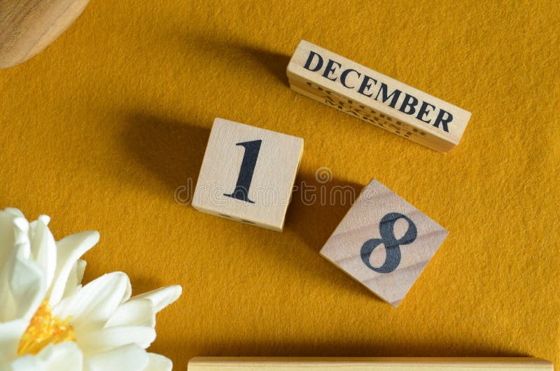 December 18, Wooden Calendar cube with yellow felt fabric with peony flower for date icon background. royalty free stock photo