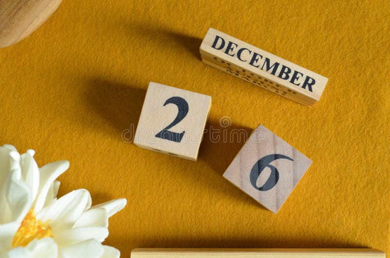 December 26, Wooden Calendar cube with yellow felt fabric with peony flower for date icon background. stock image