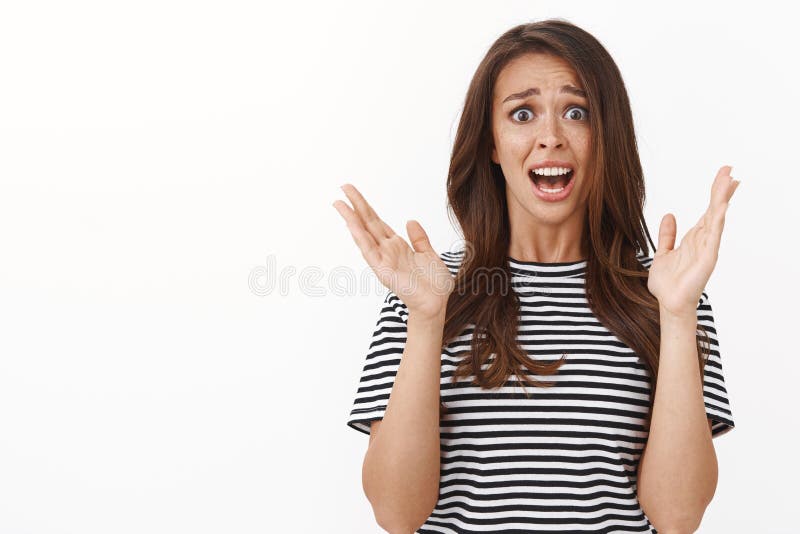 Decepcionado se refiere a la guapa guapa hembra con pecas en camisetas a rayas levantando las manos desesperada y imagen de archivo