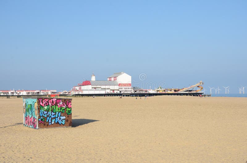 Deckchair dzierżawienia buda na plaży przy Wielkim Yarmouth z przyjemności molem w tła i graffitti budzie przy przodem zdjęcie royalty free Deckchair dzierżawienia buda na plaży przy Wielkim Yarmouth z przyjemności molem w tła i graffitti budzie przy przodem zdjęcie royalty free