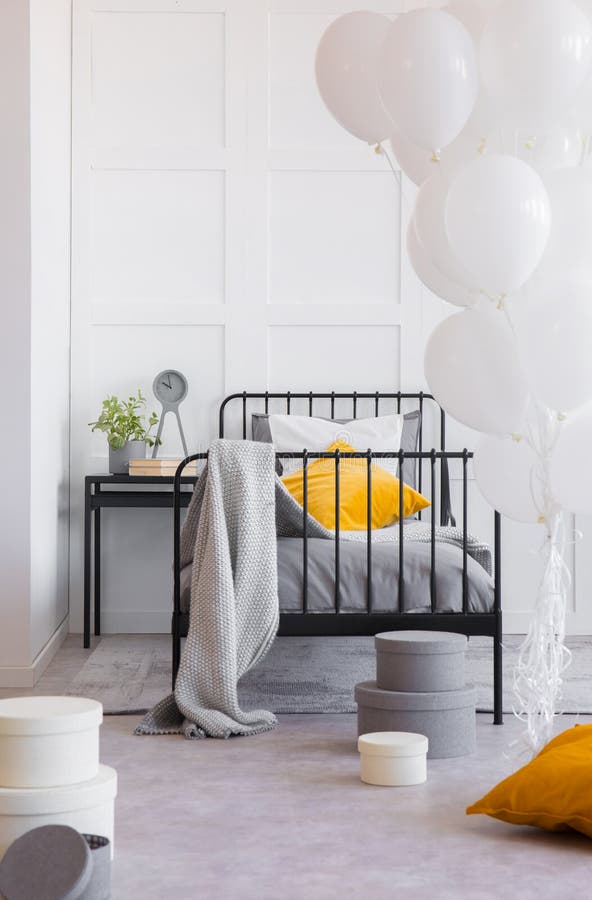 Decke und orange Kissen auf Bett im Innenraum mit Ballonen Reales Foto lizenzfreie stockfotos Decke und orange Kissen auf Bett im Innenraum mit Ballonen Reales Foto lizenzfreie stockfotos