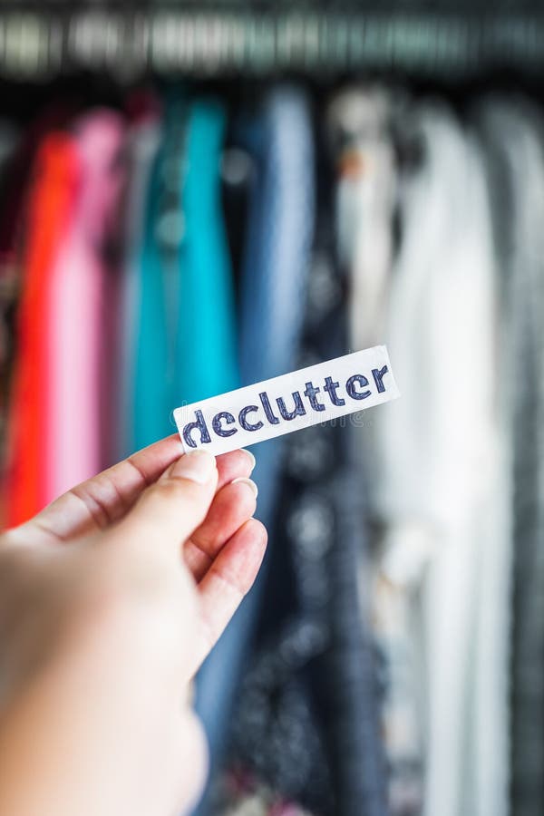 shopping and consumerism, Declutter sign held in front of wardrobe full of clothes stock photography