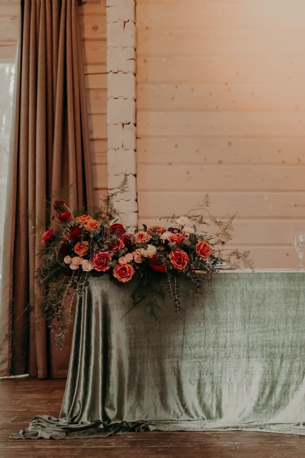 Decor of a festive wedding table decorated with a large bouquet, lanterns and candles in green and red colors.