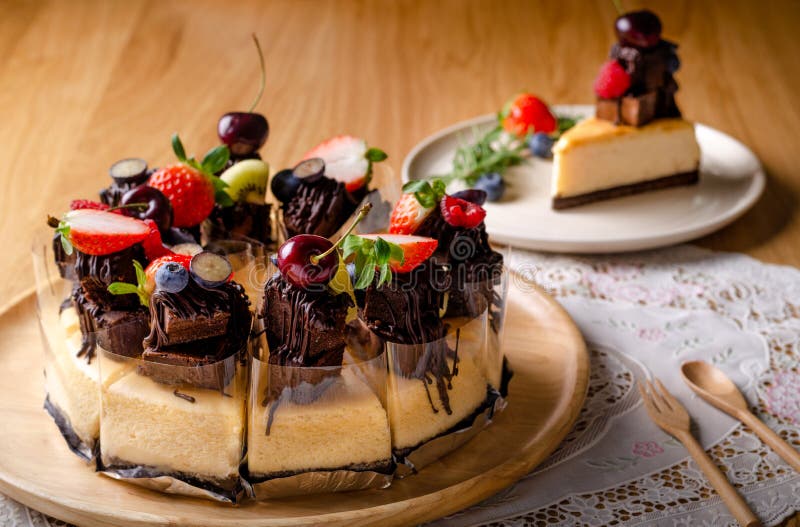 Bolo de queijo de brownie caseiro em chapa branca, decorado com morangos,  mirtilo e cereja, no jogo americano estilo inglês, na mesa de madeira.  usado para decorar a loja.