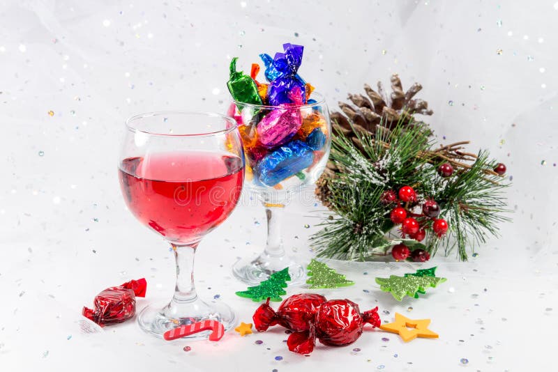 Christmas party table decorations with wine and wrapped chocolate candy sweets. Treats to enjoy the merry holiday season.on a snowy white background. Christmas party table decorations with wine and wrapped chocolate candy sweets. Treats to enjoy the merry holiday season.on a snowy white background.