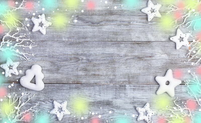 Decoraciones navideñas Marco blanco de estrellas navideñas, panecillos, ramas, nieve y luces sobre fondo blanco de madera foto de archivo libre de regalías Decoraciones navideñas Marco blanco de estrellas navideñas, panecillos, ramas, nieve y luces sobre fondo blanco de madera foto de archivo libre de regalías