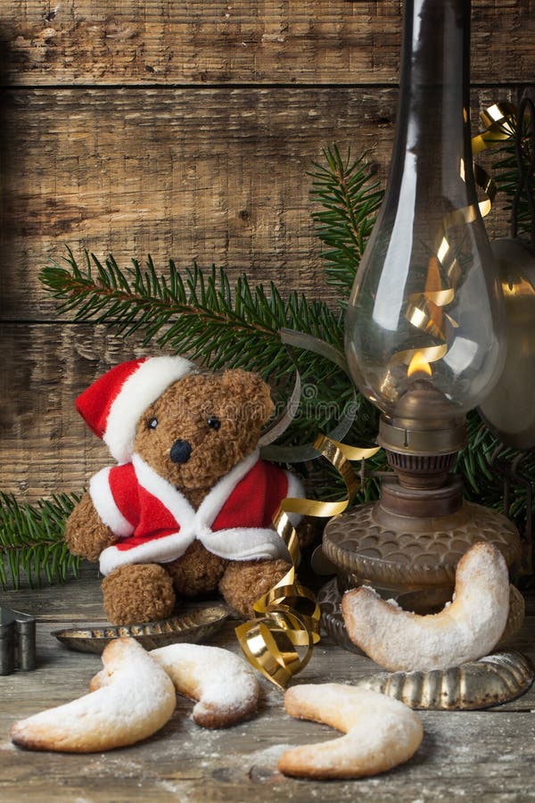 Christmas decoration with antique teddy bear in santa`s hat with burning vintage lamp and sugar cookies over wooden background. Christmas decoration with antique teddy bear in santa`s hat with burning vintage lamp and sugar cookies over wooden background